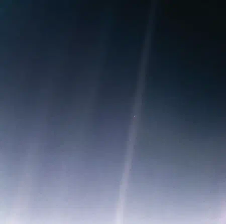 The Pale Blue Dot image: Earth as a tiny point of light within a band of scattered sunlight.